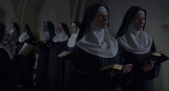 Movie still from “The Innocents” (2016), directed by Anne Fontaine – A group of women dressed as nuns holding books; Medium shot, Low angle
