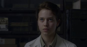 Movie still from “The Innocents” (2016), directed by Anne Fontaine – A woman with blue eyes wearing a white coat; Close Up shot, Over the shoulder angle