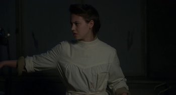 Movie still from “The Innocents” (2016), directed by Anne Fontaine – A woman in a white shirt is standing in a dark room; Medium shot, Low angle