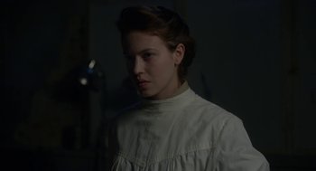 Movie still from “The Innocents” (2016), directed by Anne Fontaine – A woman in a white shirt is standing in the dark; Close Up shot, Low angle