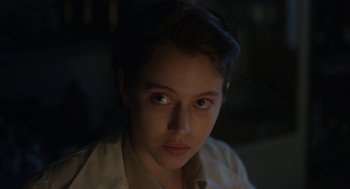 Movie still from “The Innocents” (2016), directed by Anne Fontaine – A young woman with a serious look on her face; Close Up shot, Over the shoulder angle