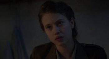 Movie still from “The Innocents” (2016), directed by Anne Fontaine – A young woman in a military jacket looking at the camera; Close Up shot, Over the shoulder angle