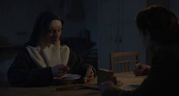 Movie still from “The Innocents” (2016), directed by Anne Fontaine – A nun sitting at a table with a plate of food; Medium shot, High angle