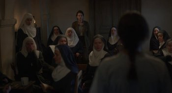 Movie still from “The Innocents” (2016), directed by Anne Fontaine – A group of women dressed as nuns sitting in a room; Wide shot, High angle