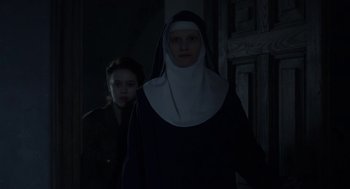 Movie still from “The Innocents” (2016), directed by Anne Fontaine – A woman and a nun standing next to each other in a dark room; Medium shot, Low angle