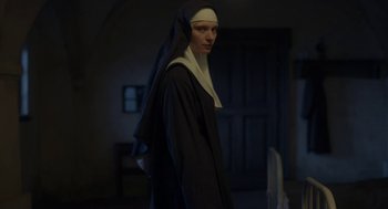 Movie still from “The Innocents” (2016), directed by Anne Fontaine – A woman dressed as a nun standing in front of a door; Medium shot, Low angle