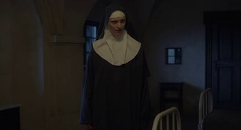 Movie still from “The Innocents” (2016), directed by Anne Fontaine – A woman dressed as a nun standing next to a chair; Medium shot, Low angle