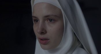 Movie still from “The Innocents” (2016), directed by Anne Fontaine – A woman wearing a white head scarf and a white head scarf; Close Up shot, Over the shoulder angle