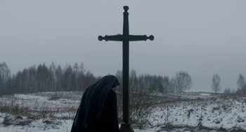 Movie still from “The Innocents” (2016), directed by Anne Fontaine – A person standing next to a cross in the snow; Wide shot, Low angle