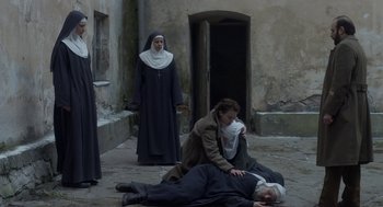 Movie still from “The Innocents” (2016), directed by Anne Fontaine – A woman kneeling down next to an old man; Wide shot, High angle