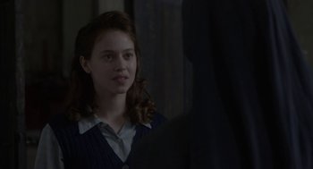 Movie still from “The Innocents” (2016), directed by Anne Fontaine – A young woman is looking at the camera in the dark; Close Up shot, Over the shoulder angle