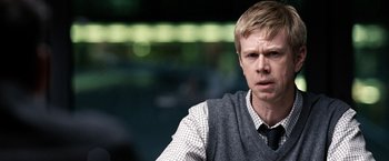 Movie still from “The International” (2009), directed by Tom Tykwer – A man in a vest and tie looking at the camera; Close Up shot, Over the shoulder angle