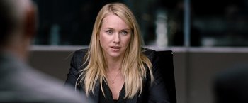 Movie still from “The International” (2009), directed by Tom Tykwer – A woman with long blonde hair sitting in a chair; Close Up shot, Over the shoulder angle