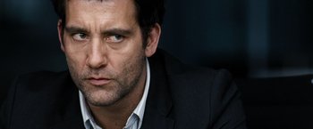 Movie still from “The International” (2009), directed by Tom Tykwer – A person wearing a suit and tie; Close Up shot, Over the shoulder angle