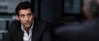 Movie still from “The International” (2009), directed by Tom Tykwer – A person wearing a suit and tie; Close Up shot, Over the shoulder angle