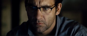 Movie still from “The International” (2009), directed by Tom Tykwer – A person wearing glasses; Close Up shot, Over the shoulder angle