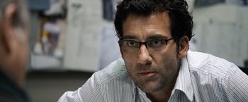 Movie still from “The International” (2009), directed by Tom Tykwer – A person wearing glasses; Close Up shot, Over the shoulder angle