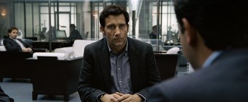 Movie still from “The International” (2009), directed by Tom Tykwer – A person wearing a suit and tie; Close Up shot, Over the shoulder angle