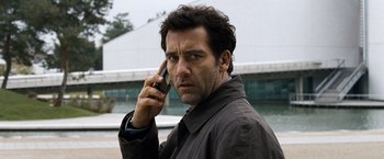 Movie still from “The International” (2009), directed by Tom Tykwer – A man holding a cell phone up to his ear; Close Up shot, Low angle