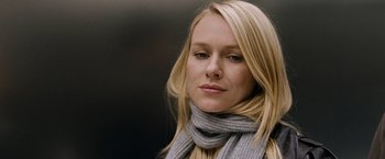 Movie still from “The International” (2009), directed by Tom Tykwer – A woman with blonde hair wearing a gray scarf; Close Up shot, Over the shoulder angle