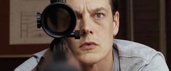 Movie still from “The International” (2009), directed by Tom Tykwer – A person looking through a telescope; Close Up shot, Over the shoulder angle