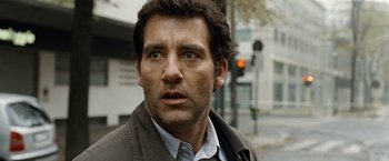 Movie still from “The International” (2009), directed by Tom Tykwer – A person wearing a jacket on a city street; Close Up shot, Over the shoulder angle