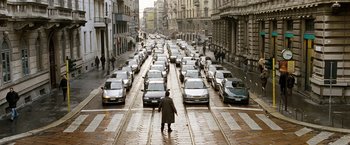 Movie still from “The International” (2009), directed by Tom Tykwer – A man walking down a street with a bunch of cars; Extreme Wide shot, High angle