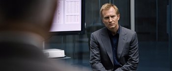 Movie still from “The International” (2009), directed by Tom Tykwer – A man sitting in front of a computer monitor; Close Up shot, Over the shoulder angle