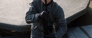 Movie still from “The International” (2009), directed by Tom Tykwer – A man holding an automatic rifle in his hands; Medium shot, High angle