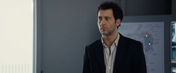 Movie still from “The International” (2009), directed by Tom Tykwer – A person wearing a suit and tie; Close Up shot, Over the shoulder angle