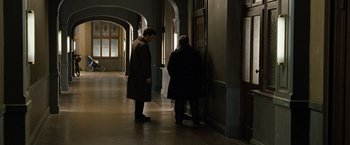 Movie still from “The International” (2009), directed by Tom Tykwer – Two men are standing in a hallway looking at each other; Wide shot, High angle