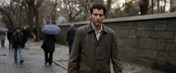 Movie still from “The International” (2009), directed by Tom Tykwer – A person wearing a jacket; Close Up shot, Over the shoulder angle