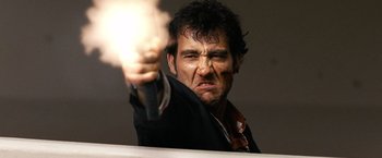 Movie still from “The International” (2009), directed by Tom Tykwer – A man holding a gun in his right hand; Close Up shot, Low angle