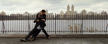 Movie still from “The International” (2009), directed by Tom Tykwer – Two men are hugging in front of a fence; Wide shot, Over the shoulder angle