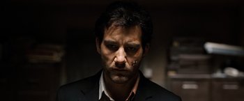 Movie still from “The International” (2009), directed by Tom Tykwer – A person wearing a suit and tie; Close Up shot, Low angle