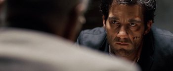 Movie still from “The International” (2009), directed by Tom Tykwer – A man's face as he looks at the camera; Close Up shot, Over the shoulder angle