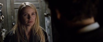 Movie still from “The International” (2009), directed by Tom Tykwer – A woman with long blonde hair looking at the camera; Close Up shot, Over the shoulder angle