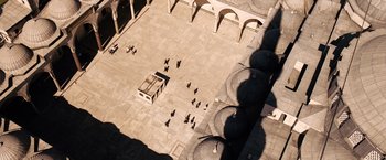 Movie still from “The International” (2009), directed by Tom Tykwer – An aerial view of people walking in an open courtyard; Extreme Wide shot, Overhead angle