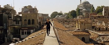 Movie still from “The International” (2009), directed by Tom Tykwer – A man running down the side of a road; Wide shot, High angle