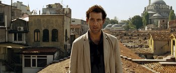Movie still from “The International” (2009), directed by Tom Tykwer – A man standing on top of a building in the desert; Close Up shot, Low angle
