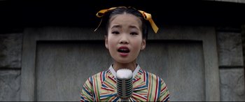 Movie still from “The Interview” (2014), directed by Evan Goldberg – A young girl is singing into a microphone; Close Up shot, Overhead angle