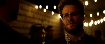 Movie still from “The Interview” (2014), directed by Evan Goldberg – A person wearing a suit and tie; Close Up shot, Over the shoulder angle