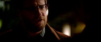 Movie still from “The Interview” (2014), directed by Evan Goldberg – A person wearing glasses and a jacket; Close Up shot, Over the shoulder angle