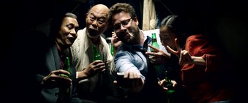 Movie still from “The Interview” (2014), directed by Evan Goldberg – A group of people standing around each other holding bottles; Medium shot, Overhead angle