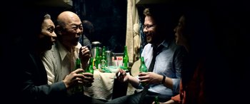Movie still from “The Interview” (2014), directed by Evan Goldberg – A group of people sitting around a table with beer; Medium shot, High angle