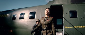 Movie still from “The Interview” (2014), directed by Evan Goldberg – A woman in a military uniform standing next to a man; Medium shot, Low angle