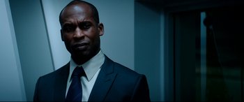 Movie still from “The Interview” (2014), directed by Evan Goldberg – A man in a suit and tie standing in front of a wall; Close Up shot, Over the shoulder angle