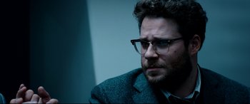 Movie still from “The Interview” (2014), directed by Evan Goldberg – A person wearing glasses and a suit; Close Up shot, Over the shoulder angle