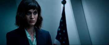 Movie still from “The Interview” (2014), directed by Evan Goldberg – A woman standing in front of an american flag; Close Up shot, Over the shoulder angle