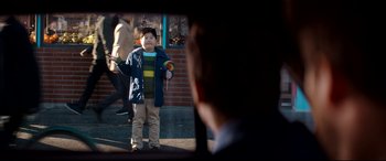 Movie still from “The Interview” (2014), directed by Evan Goldberg – A young boy holding a lollipop in front of an older man; Medium shot, Over the shoulder angle